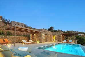 A poolside area with lounge chairs, a stone building, and a pergola. - Mythic Villa (Sifnos)