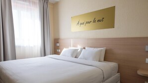 Ein Hotelzimmer mit einem großen Bett, einem Kopfteil, einem Nachttisch und einem an der Wand befestigten Schild.