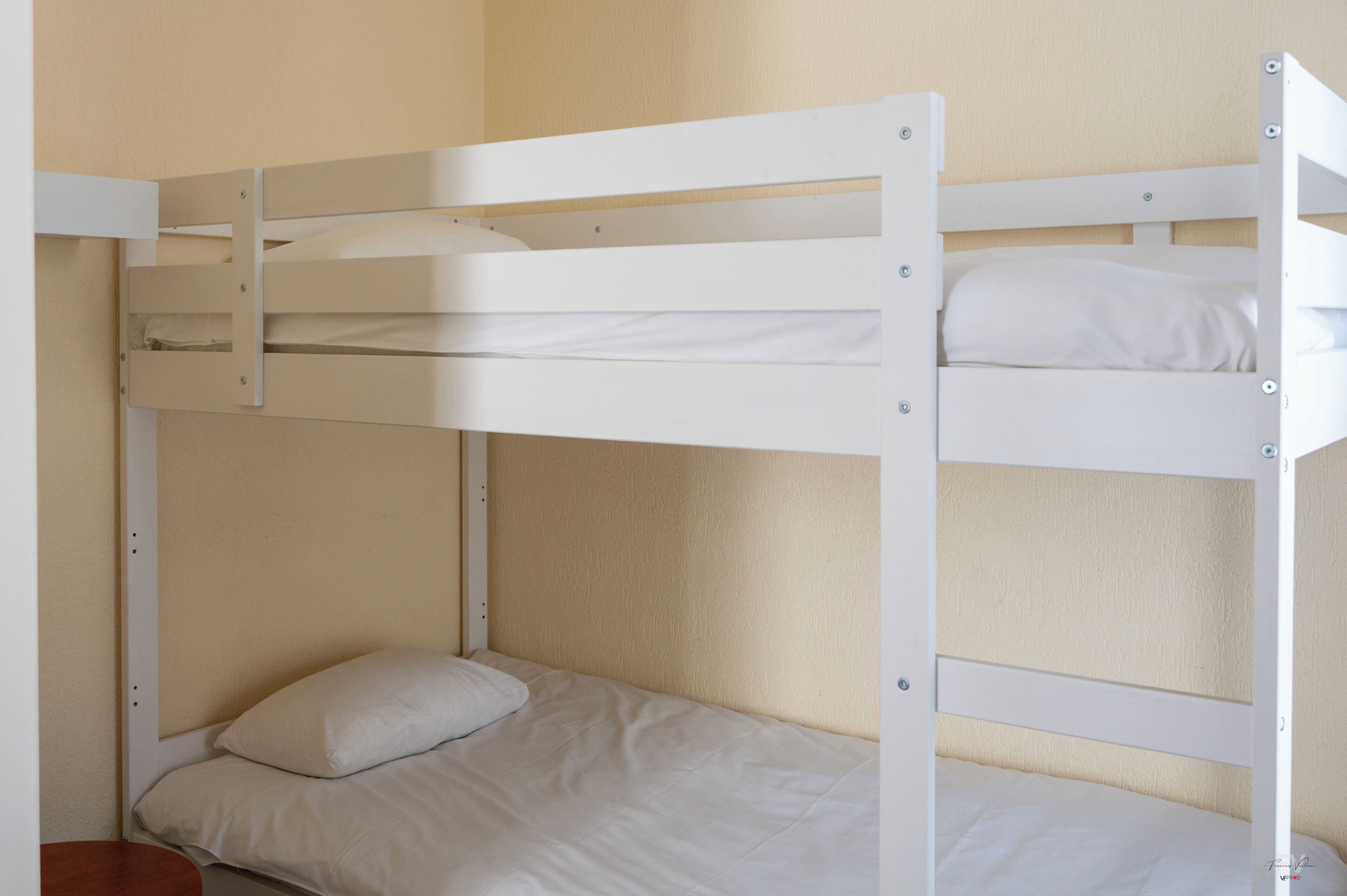 Una cama litera con dos niveles, una cama individual en la parte inferior y un cabecero de madera.