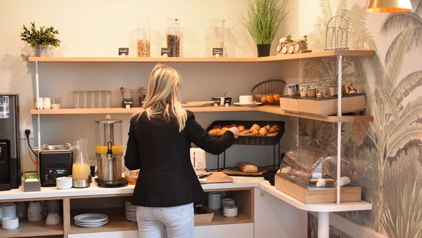 Ein Frühstücksbuffet mit einer Kaffeemaschine, einer Obstauslage und einer Auswahl an Gebäck.