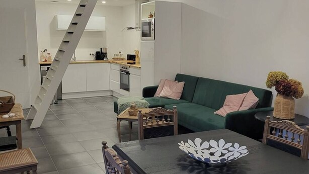 Ein moderner Wohnraum mit Essbereich, einem grünen Sofa und einer Treppe, die zu einer oberen Ebene führt.