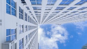 A modern building with a symmetrical facade, multiple floors, and a clear sky with clouds. - 1 bdr apartment with Ocean View and Social area w/ pool (Avenida Balboa)