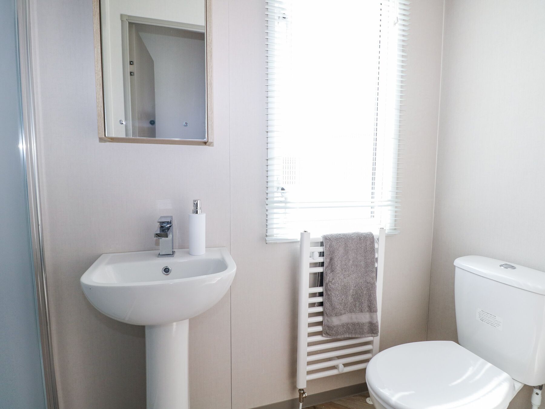 A bathroom with a white sink, a toilet, and a towel rack.