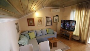 Een woonkamer met een bank, een salontafel, een televisie en een lamp.