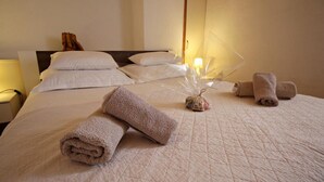 Een keurig opgemaakt bed met opgerolde handdoeken en een decoratief middelpunt.