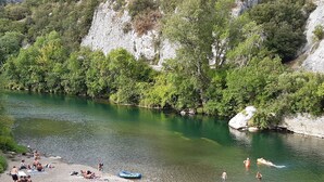 A riverside beach with people sunbathing and swimming.