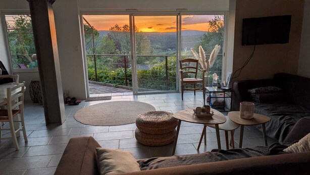A living room with a sofa, a coffee table, a chair, and a TV mounted on the wall.