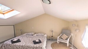 A bedroom with a bed, two bedside tables, a chair, a lamp, and a window.