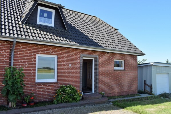 A single-story brick house with a tiled roof, a front door, and a small attached garage.