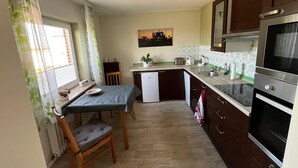 Eine kleine Küche mit Essbereich, Holzschränken, einem Geschirrspüler und einem großen Backofen.