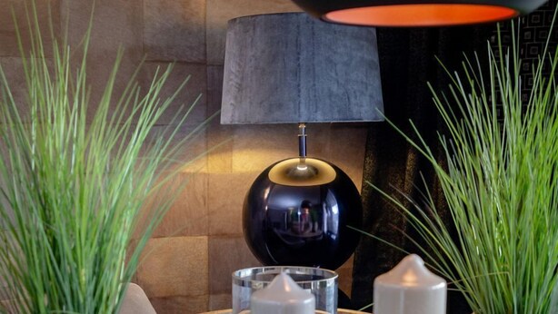 A dining table set with glassware, a candle, and a lamp. - Langschläfer - New: Apartment Langschläfer 4th floor, best location on the beach (Westerland)