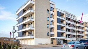 A multi-story residential building with balconies, a parking area, and a clear sky. - Langschläfer - New: Apartment Langschläfer 4th floor, best location on the beach (Westerland)