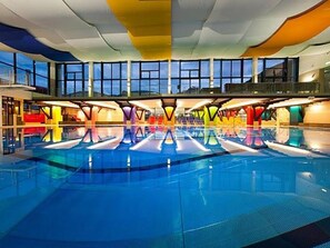 An indoor swimming pool with a modern design, featuring a large open space and a high ceiling. - Standard double room - Hotel Gasthof Mitteregger (Kaprun)