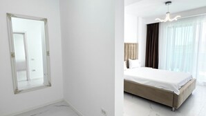 Um quarto espaçoso e moderno, com uma cama grande, um espelho e um candelabro.