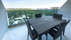 Uma varanda com mesa e cadeiras, com vista para o horizonte urbano e áreas verdes.