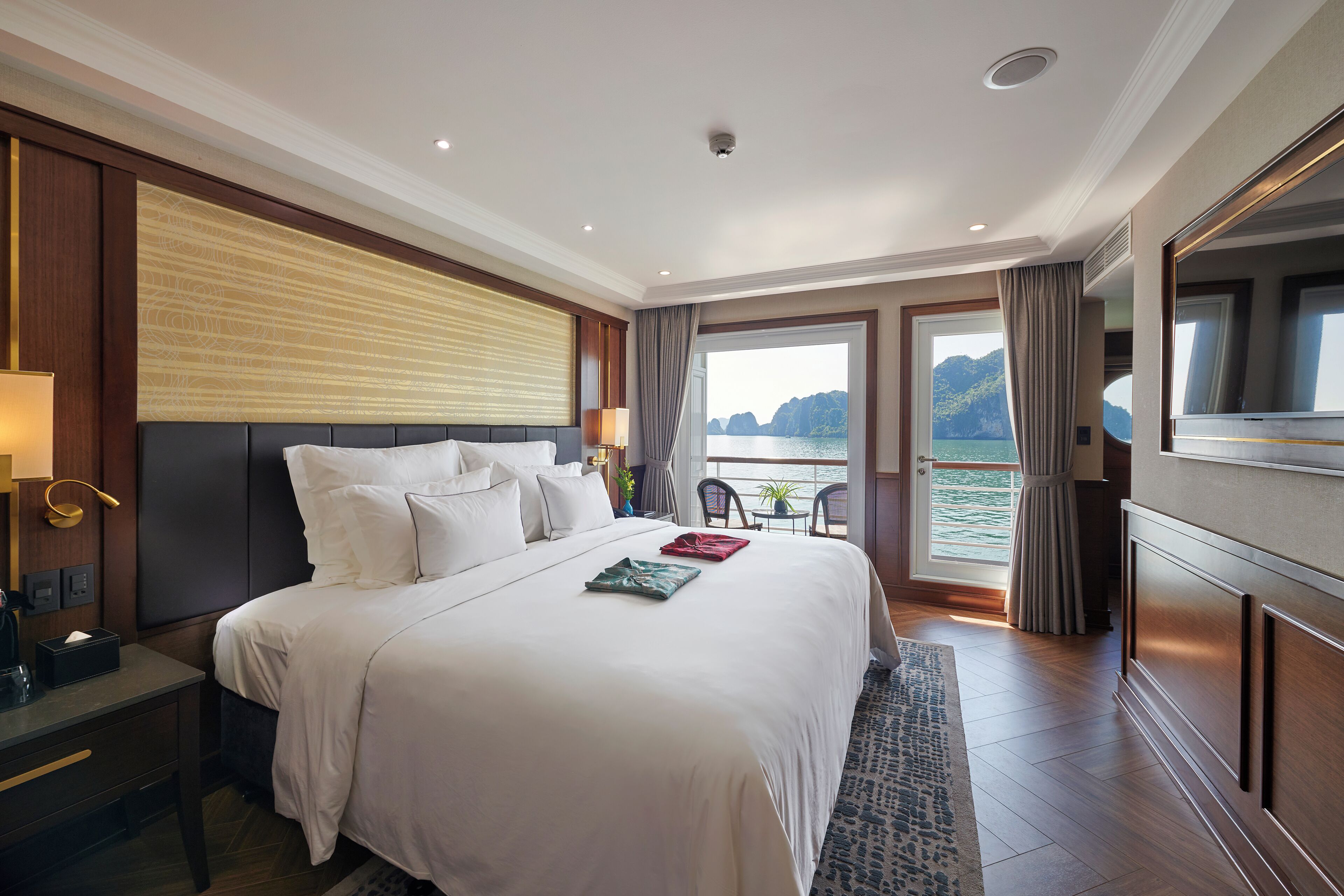 A spacious hotel room with a large bed, a desk, and a view of the sea.