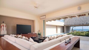 Ein modernes Wohnzimmer mit einem großzügigen Ecksofa, einem Flachbildfernseher und einem Holztisch.