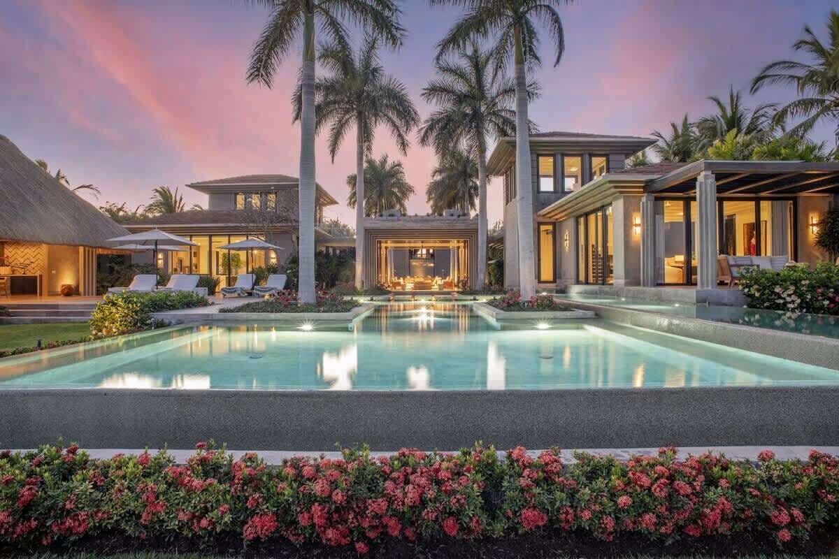 Ein luxuriöses Resort mit großem Pool, Palmen und einem gut beleuchteten Außenbereich.