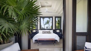 A bedroom with a large bed, a bench, and a view of palm trees outside. - Casa Cascada: 6BR Luxury Villa + Infinity Pool & Chef (Punta Mita)