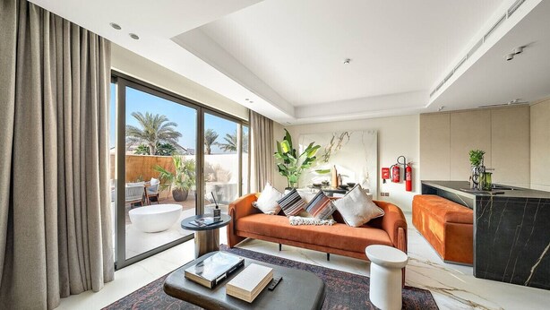 A modern living room with a sofa, coffee table, and a view of the outdoors. - Peaceful 4BR Villa in Jumeirah Golf Estates with Garden Views (Jumeirah Golf Estate)