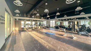 A spacious gym with various exercise equipment, large windows, and modern pendant lighting. - Peaceful 4BR Villa in Jumeirah Golf Estates with Garden Views (Jumeirah Golf Estate)