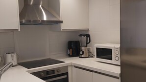 A modern kitchen with stainless steel appliances, including a microwave, coffee maker, and toaster. - Spacious Family Apartment in Málaga, near historic center (Málaga)