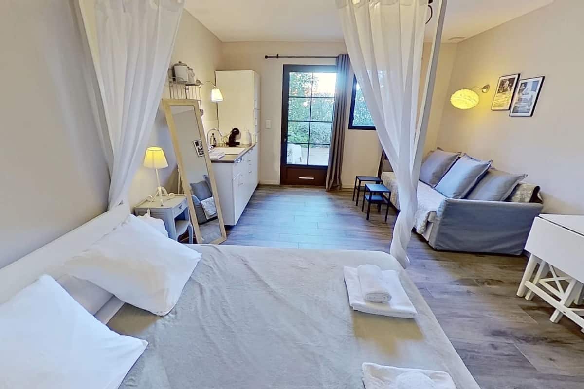 A hotel room with a bed, a desk, a chair, and a sofa.