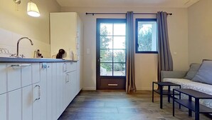 Eine kleine Küche mit weißen Schränken, einem Spülbecken und einem Fenster mit Vorhängen.