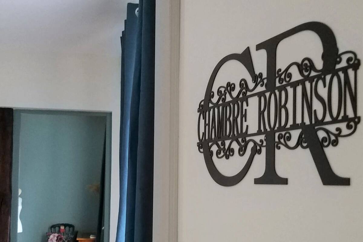 Ein Zimmer mit einer Tür, deren dekorative Namensschildchen "CHAMBRE ROBINSON" zeigt.
