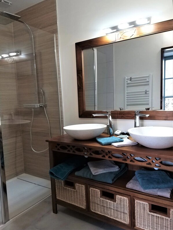 Une salle de bain avec deux lavabos, un grand miroir et une cabine de douche.