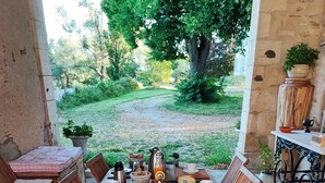 An outdoor dining area with a long wooden table set for a meal, surrounded by chairs, with a view of a garden and trees in the background. - Chambres d'hôtes Au Bord De Loire (La Marche)