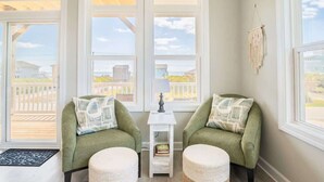 A cozy room with two green armchairs, a small white side table with a lamp, and a macrame wall hanging. - Still Waters - Waterfront - NEW Design Build Home - Ocean View (North Topsail Beach)