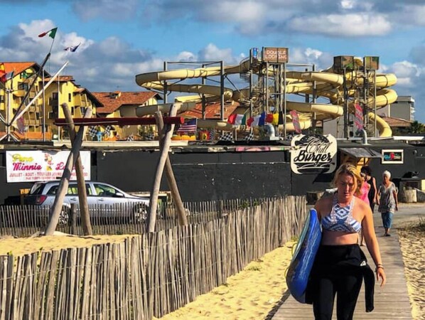 A beachside walkway with a water slide structure in the background. - Seignosse Villa (Seignosse)