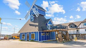 A building with a windmill, a covered outdoor area, and a staircase leading to a second floor.