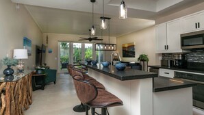 A modern kitchen with a central island, bar stools, and a ceiling fan. - Serenity Villa- Steps from Beach, Family Friendly (Cruz Bay)