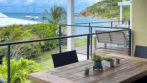 A balcony with a wooden table, chairs, and potted plants. - Serenity Villa- Steps from Beach, Family Friendly (Cruz Bay)