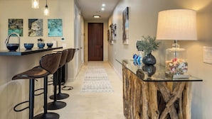 A modern kitchen with a bar area, wooden stools, and decorative items on the counter. - Serenity Villa- Steps from Beach, Family Friendly (Cruz Bay)