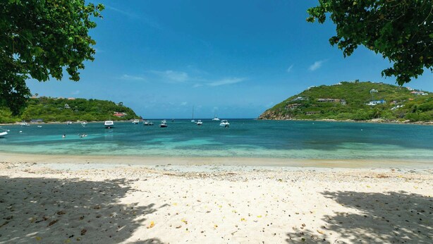 A beach with clear turquoise water, boats, and a sandy shore. - Nautilus- Beach Front with 3 King Suites (Cruz Bay)