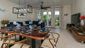A dining area with a wooden table set for four, surrounded by wicker chairs. - Nautilus- Beach Front with 3 King Suites (Cruz Bay)