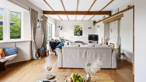 Ett mysigt vardagsrum med en soffa, ett soffbord med frukt och en vas, en öppen spis och en tv.