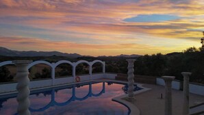 Una piscina con vistas a montañas al atardecer.