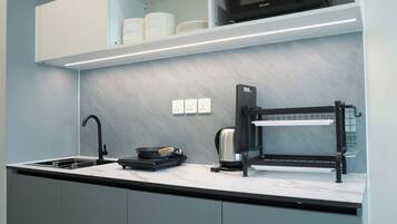 A modern kitchen with a built-in microwave, a kettle, and a coffee machine.