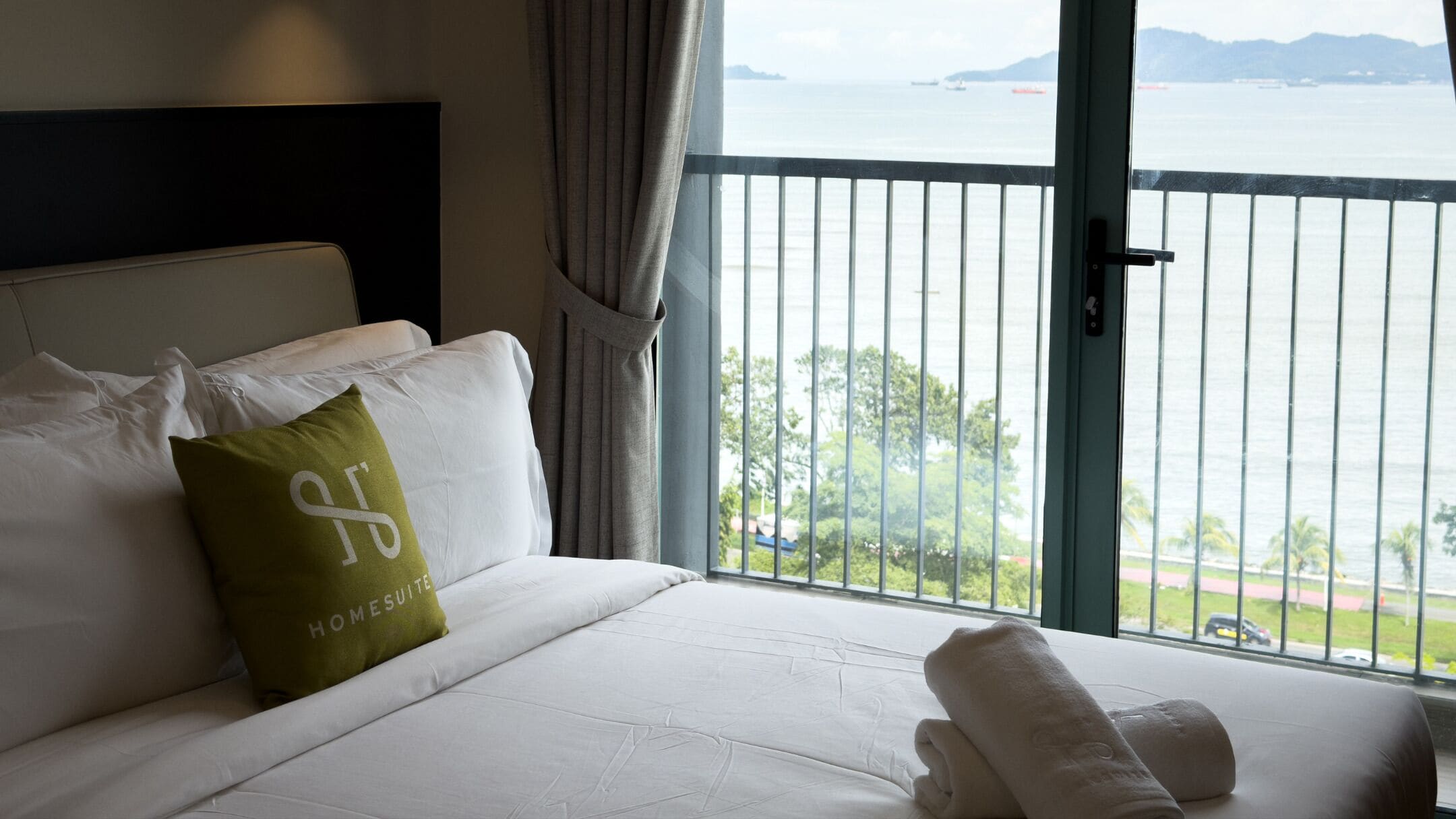 A hotel room with a bed, a view of the sea, and a balcony.