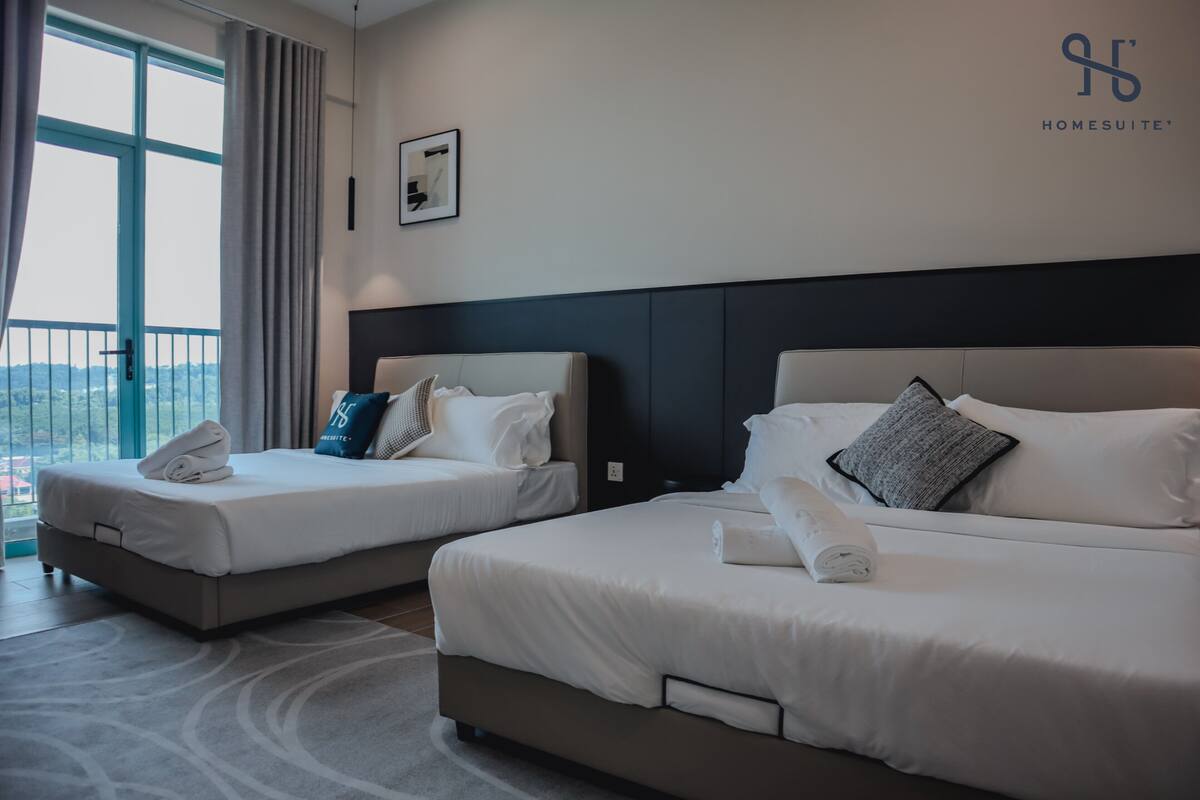 A hotel room with two beds, a large window with a view, and a logo on the wall.