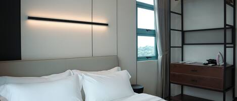Una habitación de hotel con cama, mesita de noche, armario y ventana con cortinas.