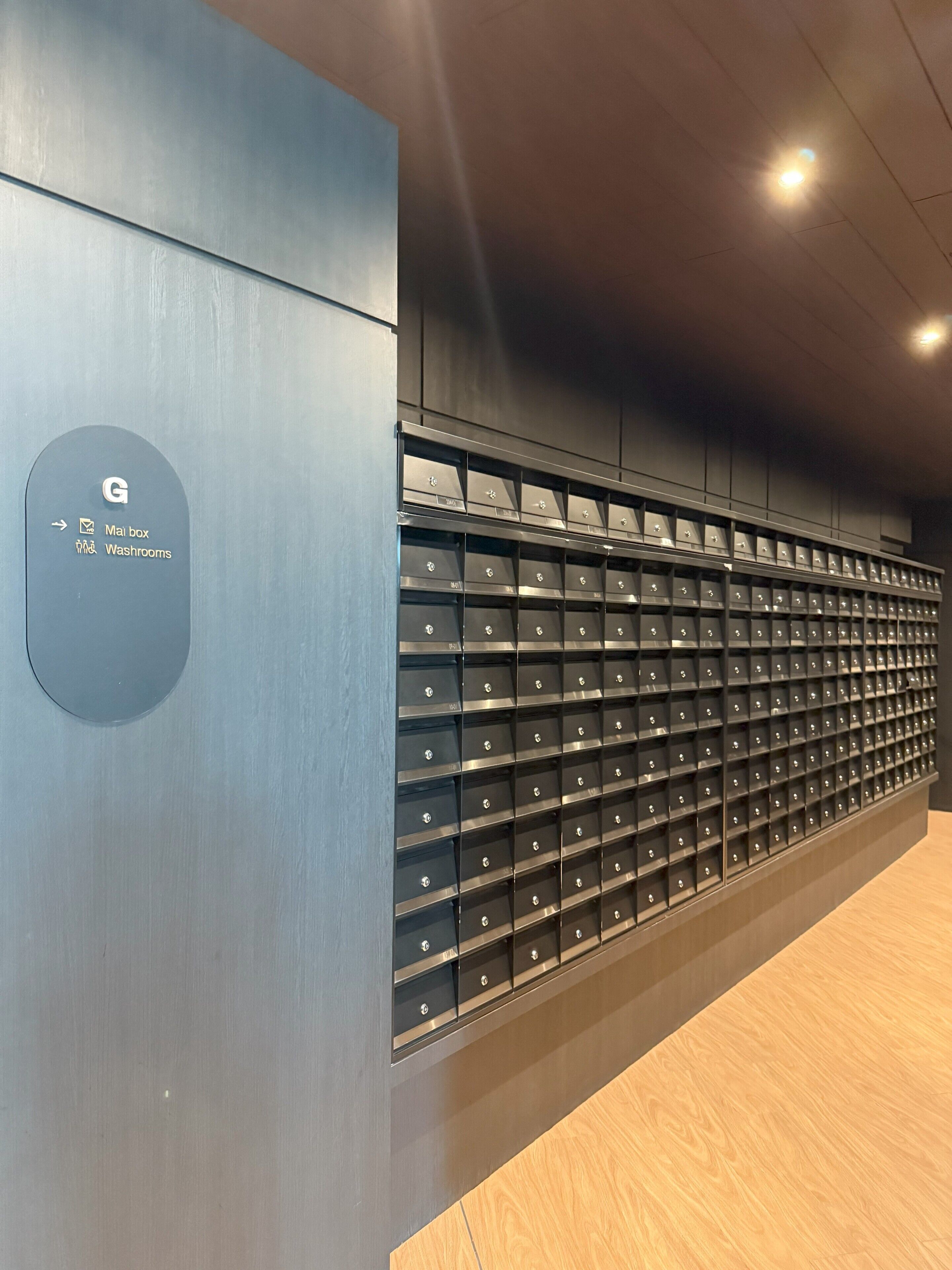 Eine Wand mit einem runden Schild, das einen Briefkasten und Toiletten anzeigt, und eine Reihe von Aufbewahrungsboxen.