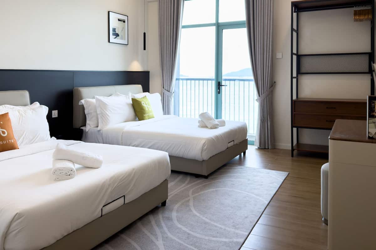 A hotel room with two beds, a desk, and a window with curtains.