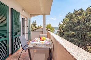 A balcony with a table set for two, overlooking a body of water and trees.