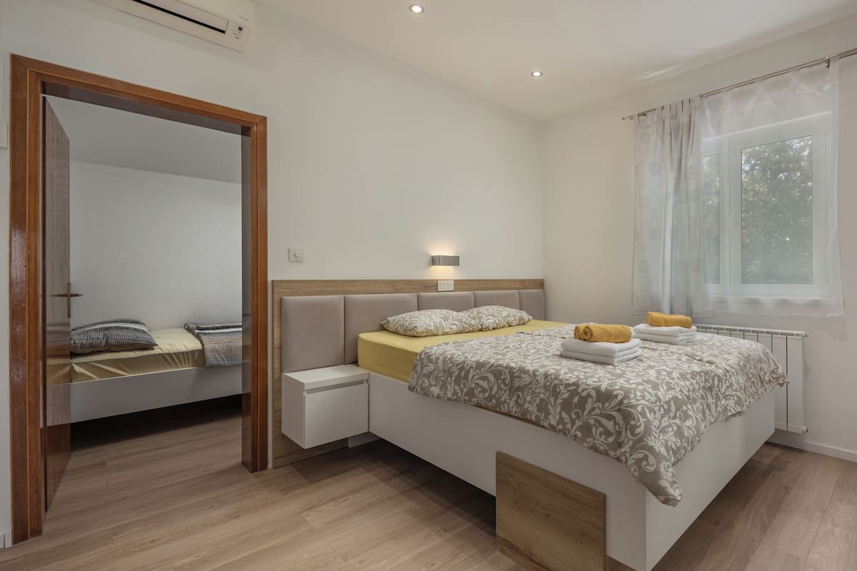 Un dormitorio moderno con cama, mesita de noche y ventana con cortinas.