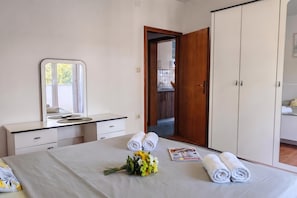Habitación de hotel con cama, escritorio, armario y baño visible a través de una puerta abierta.